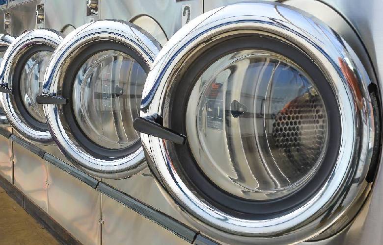 Vooraanzicht van een rij wasmachines in een wasserette met een industriële waterverzachter.